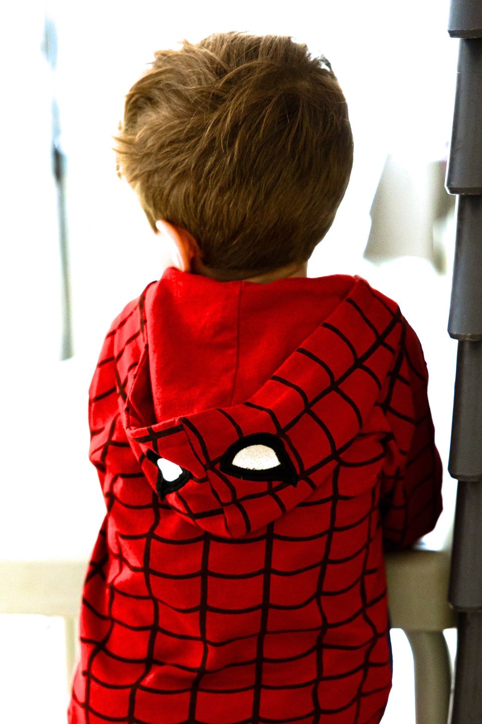 Un bambino di spalle con una felpa rossa da supereroe