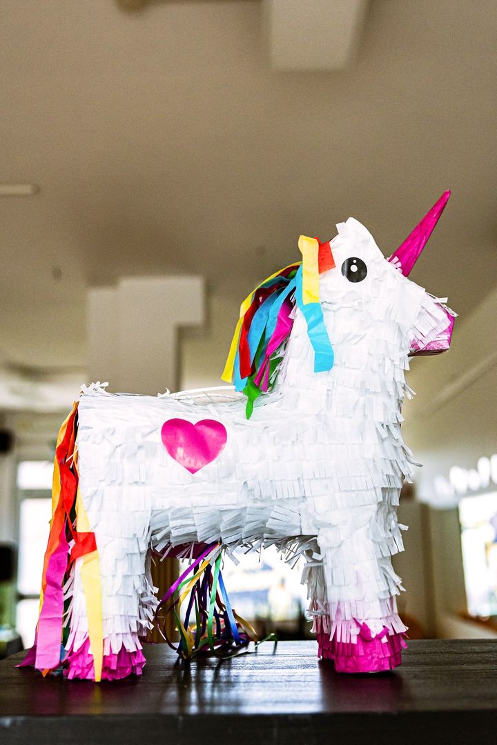 Una pentolaccia a forma di unicorno bianco con la criniera arcobaleno