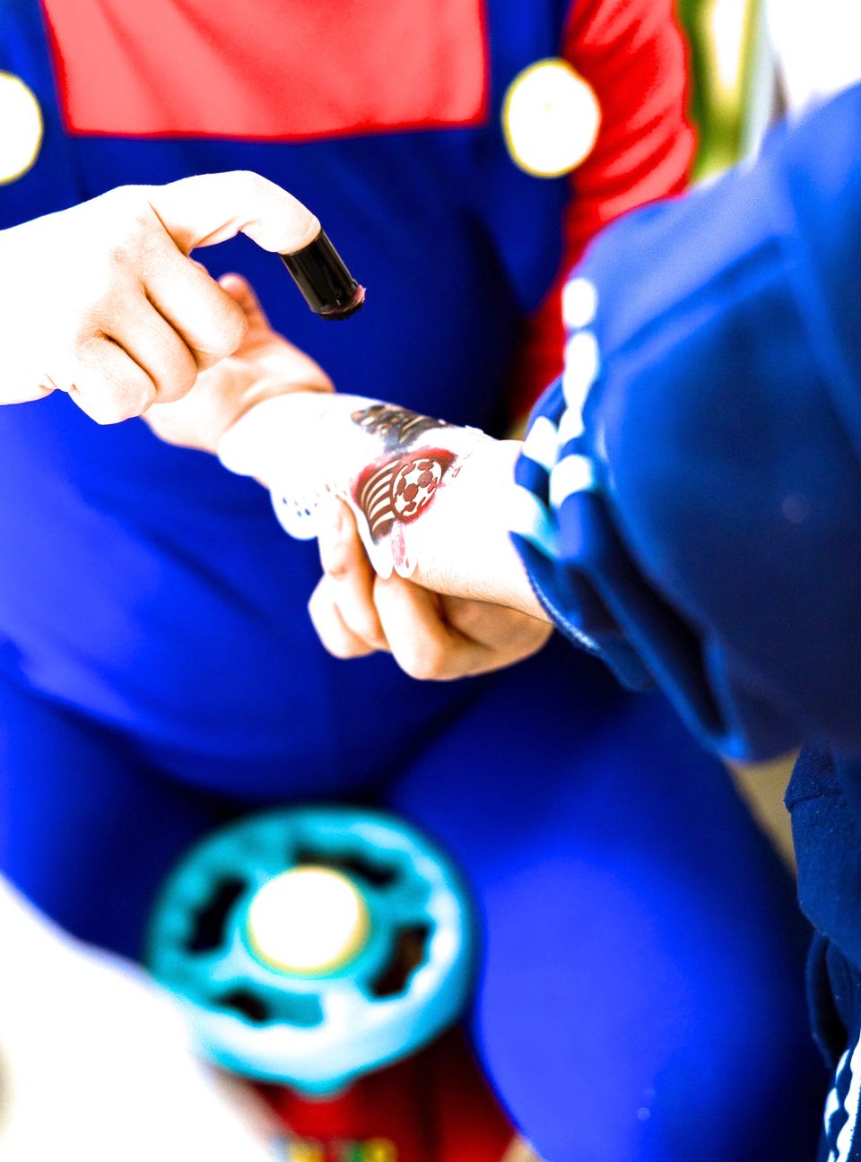 Un animatore in costume rosso e blu applica un tatuaggio finto sulla mano di un bambino